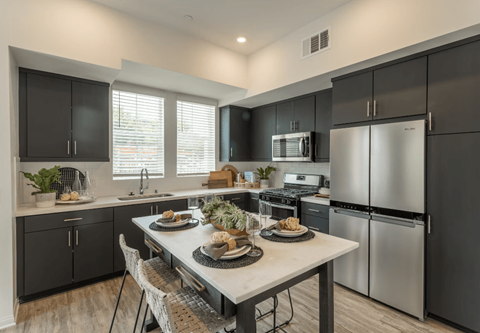 a kitchen with stainless steel appliances and a table with plates of food at Citron Apartment Homes, Riverside, 92506